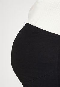 Svart, stretchig kjol i ett mjukt tyg. Har en hög midja som är designad för att forma sig runt en rundad siluett.