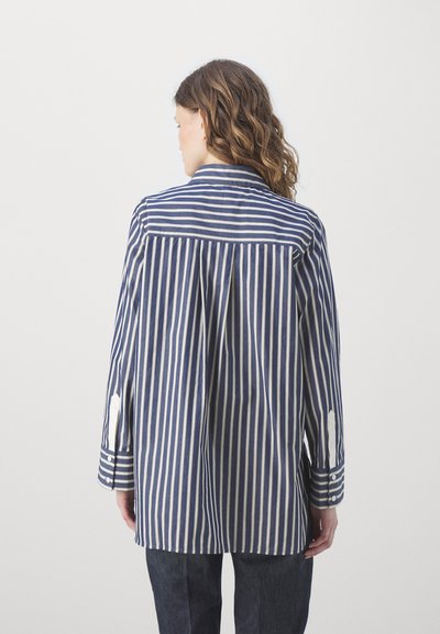Camicia a righe con strisce verticali blu navy e bianche, maniche lunghe con polsini abbottonati, una piega sul retro e colletto classico.