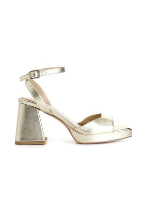 Guld metallic blokhæl sandal med ankelrem og åben tå, med lav plateau-sål og spænde lukning.