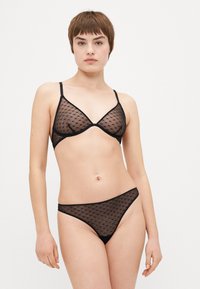 Black sheer lingerie set featuring a triangle bralette and matching thong. Both pieces have small heart patterns and thin straps.