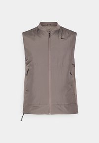 Gilet senza maniche con zip, di colore taupe chiaro. Realizzato in un tessuto leggero e liscio con una leggera lucentezza. Presenta due tasche laterali e un elastico sull'orlo.