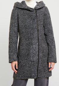 Manteau gris texturé avec fermeture éclair, capuche et manches longues. Le tissu présente un motif moucheté, offrant chaleur et douceur.