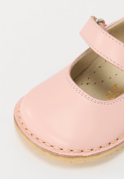 Rosa skinn Mary Jane-sko med stropp, avrundet tå, sydd kant, og myk indre fôr. Har et utskåret område for pusteevne.