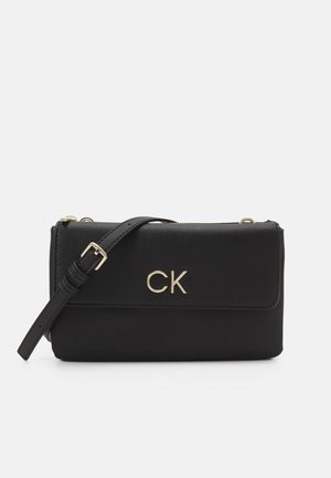 Schwarze Leder-Umhängetasche mit verstellbarem Riemen und goldenem "CK"-Logo auf der vorderen Klappe, vor weißem Hintergrund.