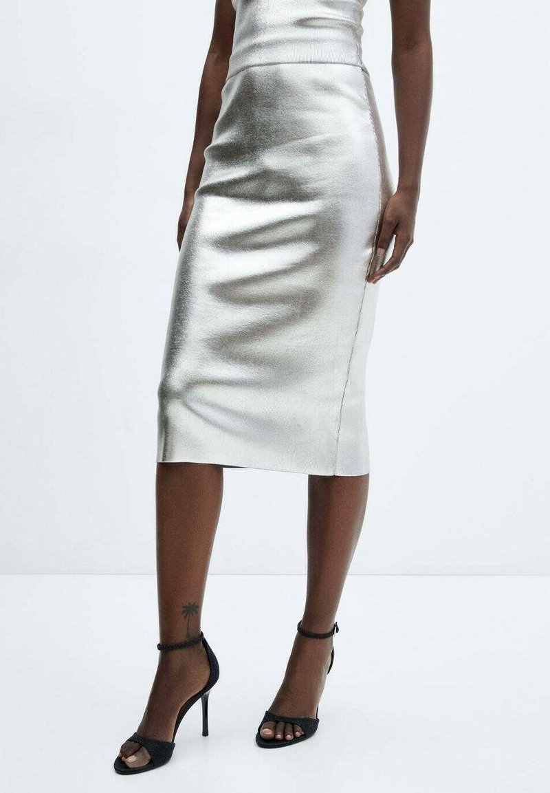 Jupe crayon argent métallique avec une silhouette cintrée, texture lisse et coupe au genou. Associée à des escarpins noirs à lanières.
