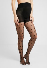 Schwarze Strumpfhosen mit Punkten und transparenter Optik, mit hohem Bund und glattem Material, die von der Taille bis zu den Zehen reichen.