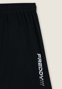 Pantaloni sportivi neri con vita elasticizzata e logo stampato "FREDDY" in bianco sulla gamba sinistra. Texture liscia, design semplice.