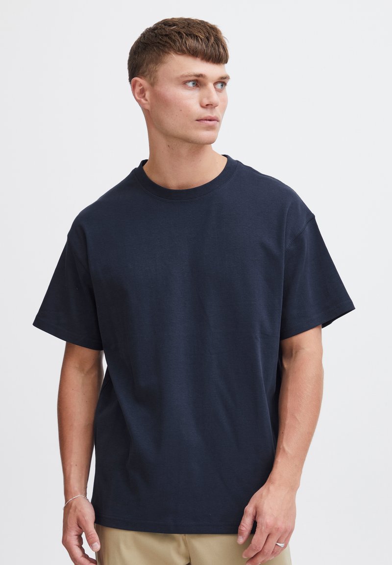 Tricou din bumbac de culoare bleu marin cu mâneci scurte, decolteu rotund, croi lejer și textură netedă, fără logo-uri sau modele vizibile.