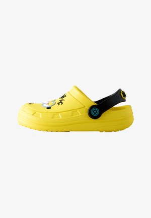 Gelber Slip-On-Clog mit schwarzem verstellbarem Fersenriemen und Cartoon-Detail auf der Oberseite, dargestellt auf weißem Hintergrund.