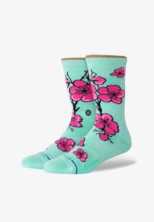 Calcetines verde menta con un patrón floral de flores de cerezo rosas con contornos negros, talón texturizado y puño acanalado en la parte superior.