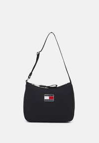 Borsa a spalla in nylon nero con zip argentata, dotata di una placca con logo arricchita con accenti rossi, bianchi e blu. Forma compatta e curvata.