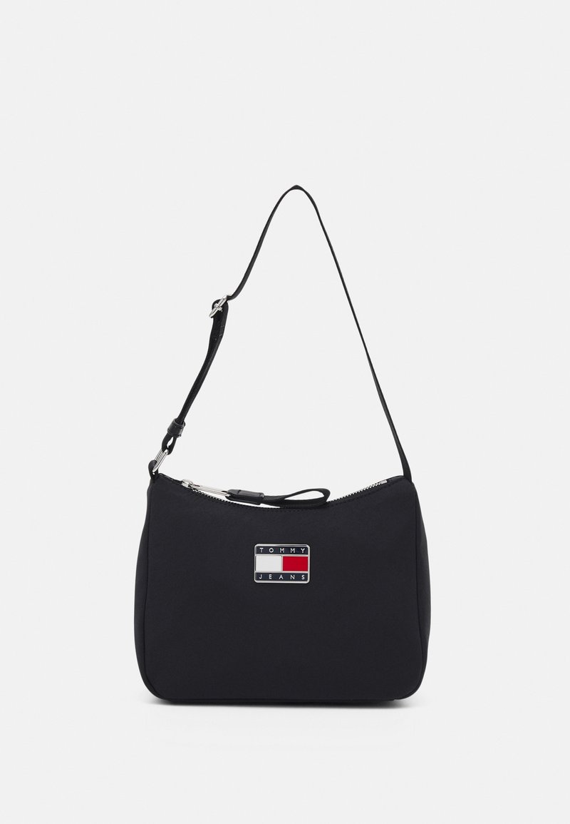 Borsa a spalla in nylon nero con zip argentata, dotata di una placca con logo arricchita con accenti rossi, bianchi e blu. Forma compatta e curvata.