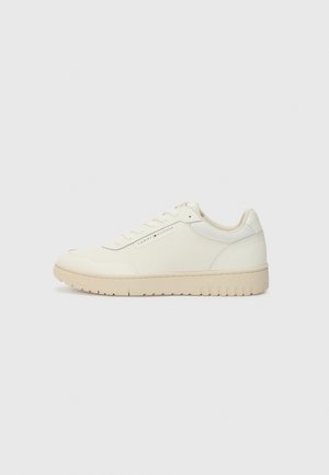 Lavprofileret beige sneakers med snørebånd, tekstureret sål og Tommy Hilfiger-logo på siden, vist fra venstre.