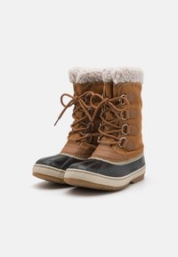 Botas de nieve impermeables marrones con una parte superior texturizada en tonalidad beige, un collar de piel sintética blanca y una parte inferior de goma negra con una suela con patrón.