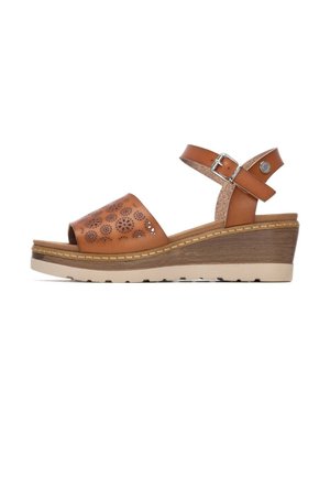 Sandalias cuña de cuero marrón con patrones florales recortados, correa en el tobillo y suela beige texturizada. Detalle de hebilla ajustable.