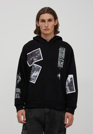 Felpa nera con tasca a marsupio, con stampe grafiche bianche e texture su davanti e maniche. Tessuto morbido, vestibilità casual.