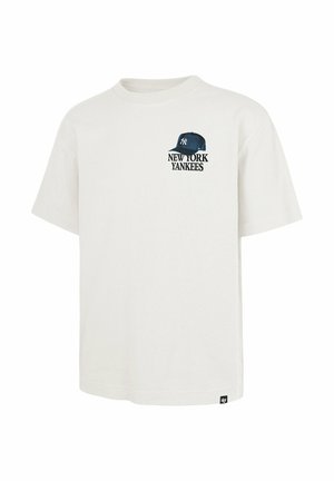 Camiseta blanca de manga corta con un pequeño gráfico de gorra de los New York Yankees en azul marino y texto en la parte superior izquierda del pecho.