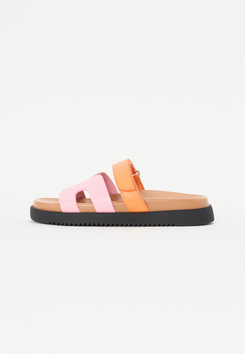 Slide sandal med rosa och orange syntetiska remmar, platt brun fotbädd och svart gummisula med ett strukturerat mönster för grepp.