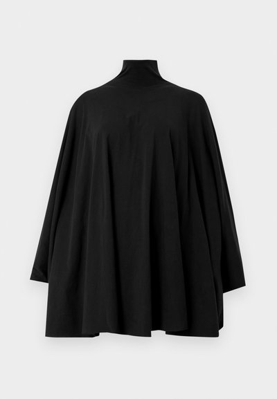 Mustat ylisuuret tunikat, joissa on korkea kaulus, pitkät hihat ja virtaava siluetti. Pehmeä kangas, jossa on minimaalista rakennetta ja ei näkyviä kiinnityksiä.