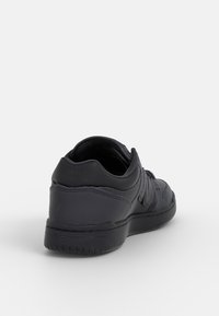 Czarne sportowe buty z gładką skórzaną cholewką, zaokrąglonym noskiem, sznurowaniem z przodu oraz subtelnym logo na pięcie.