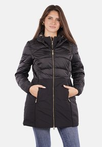 Giacca a vento nera con zip frontale, design trapuntato, tasche laterali e cappuccio staccabile. Presenta accenti in hardware color oro.