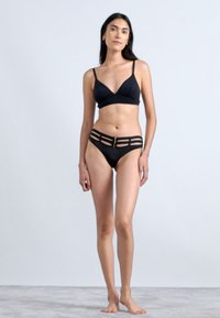 Fekete bikini szett, amely triánguláris bralette-ből áll, állítható pántokkal és magas derekú alsórészből, amelyen kivágások és középső fém rész található.