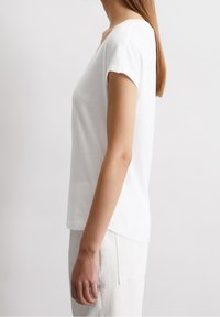 Vit t-shirt med kort ärm som har en avslappnad passform, rund halsringning och mjukt bomullstyg, med rak nederkant och utan synliga mönster.