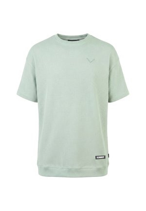 T-shirt vert clair à manches courtes en tissu gaufré, col rond, avec une petite étiquette "KLEINIGKEIT" près de l'ourlet sur le côté droit à l'avant.