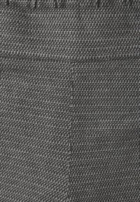 Tela texturizada en un patrón gris y negro, con un tejido apretado, un brillo sutil y costuras visibles a lo largo de los bordes.