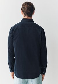 Marineblå kordfløjls-skjorte med knapper, lange ærmer, blød tekstur og klassisk krave, med knappede manchetter og en lige snit.