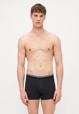 Schwarze Baumwoll-Boxershorts mit einer enganliegenden Passform, ausgestattet mit einem gestreiften elastischen Bund und einer Fronttasche. Glatte Textur.