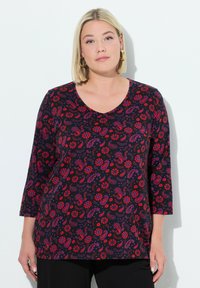 Schwarzes Oberteil mit V-Ausschnitt und Dreiviertelärmeln, das ein rotes und lila Paisley-Blumenmuster auf weichem Stoff zeigt.