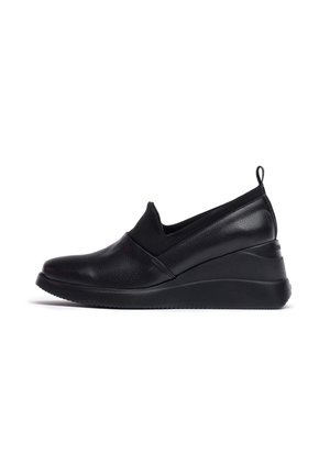 Zapatos negros tipo deslizante hechos de cuero texturizado con una parte superior de tela suave. Cuentan con un tacón de cuña y una suela de goma para mayor agarre.