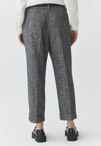 Gray wool trousers with a textured finish, a relaxed fit, cuffed hems, and two back pockets, paired with black shoes.