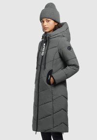 Manteau d'hiver long gris avec un motif matelassé diagonal, capuche ajustable, fermeture éclair, poches latérales et détail de logo à l'avant.