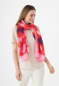 Foulard coloré avec de grands motifs en cœur dans des teintes de rouge, rose et violet, avec une bordure texturée et un tissu doux et léger.