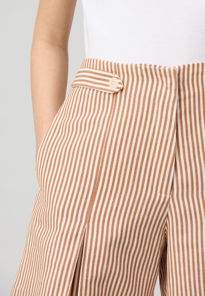 Pantalones a rayas confeccionados en una tela con rayas verticales marrones y crema alternas. Bolsillo delantero con un pequeño detalle de botón en la cinturilla.