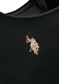 Czarna torba z fakturowanej skóry z emblematem logo w złotym odcieniu przedstawiającym jeźdźca na koniu, umieszczonym wyraźnie z boku.