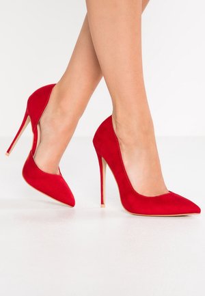 Escarpins en daim rouge à talons hauts avec un bout pointu et des côtés découpés. Dotés d'un talon stiletto fin et d'une texture lisse et mate.