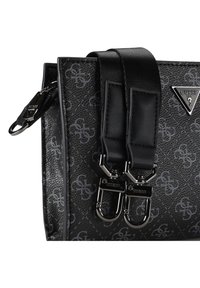 Schwarze Tasche aus synthetischem Leder mit strukturierter Oberfläche und grauen Logomustern, zwei schwarzen Trägern und silbernen Beschlägen.