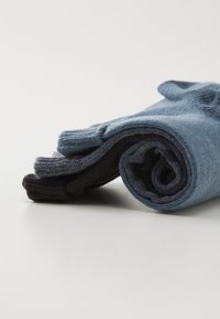 Par de calcetines enrollados con un diseño en gris oscuro y azul claro. Textura de punto suave con acentos acanalados en las aberturas.