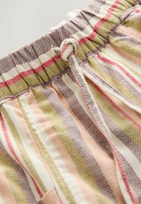 Ceinture élastique avec un nœud coulissant sur un tissu à rayures présentant des lignes verticales dans des tons rose pâle, vert olive, beige et marron.