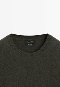 Maglione in cashmere verde scuro con scollatura rotonda, polsini e orlo a coste. L'etichetta riporta "Massimo Dutti, 100% cashmere, realizzato in Cina."