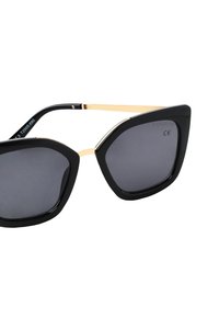 Ochelari de soare negri supradimensionați, cu o formă hexagonală, lentile întunecate și brațe din metal de culoare aurie. Prezintă un finisaj lucios și o marcă subtilă.