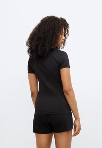 Black short-sleeve top made of cotton, featuring a fitted design and a round neckline, paired with matching black shorts.