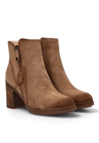 Botas de ante marrón hasta el tobillo con tacón cuadrado, cremallera lateral y detalles de costura. Textura suave con punta redondeada.
