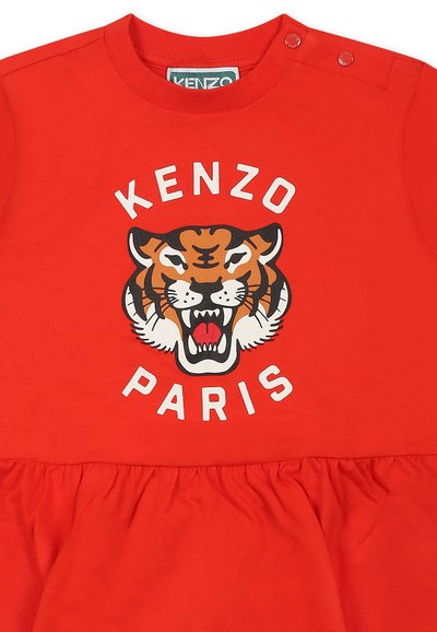 Czerwona bawełniana sukienka z grafiką tygrysa i napisem "KENZO PARIS". Okrągły dekolt z zapięciami na zatrzask oraz rozkloszowany, marszczony dół.