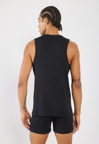 Conjunto de top sin mangas de canalé negro y pantalones cortos, que muestra un ajuste ceñido y una textura suave, sin patrones visibles ni detalles de hardware.