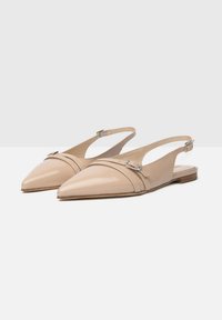 Scarpe slingback in vernice beige con punta affusolata, una fascetta decorativa con dettaglio a fibbia e una suola piatta in legno.