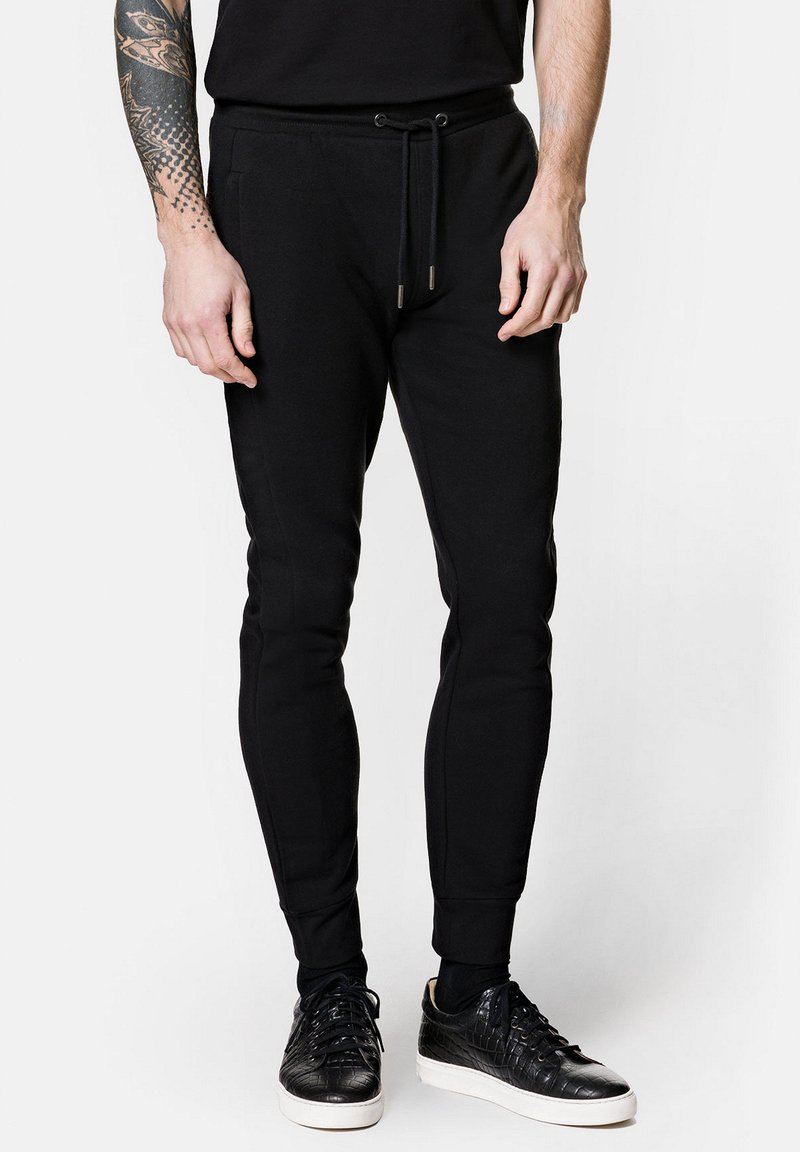 Czarne dresy wykonane z miękkiego materiału, z elastycznym pasek w talii, zwężanymi nogawkami i ściągaczami. W połączeniu z czarnymi teksturowanymi trampkami.